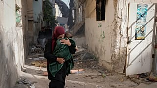 امرأة فلسطينية تحمل طفلًا وتهرب في أحد شوارع مخيم جنين بعد اجتياحه من قبل الجيش الإسرائيلي