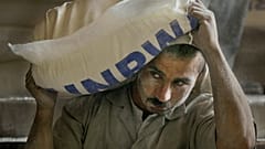 عامل فلسطيني يحمل كيساً من الدقيق بعد تفريغه من شاحنة في مركز توزيع تابع للأونروا