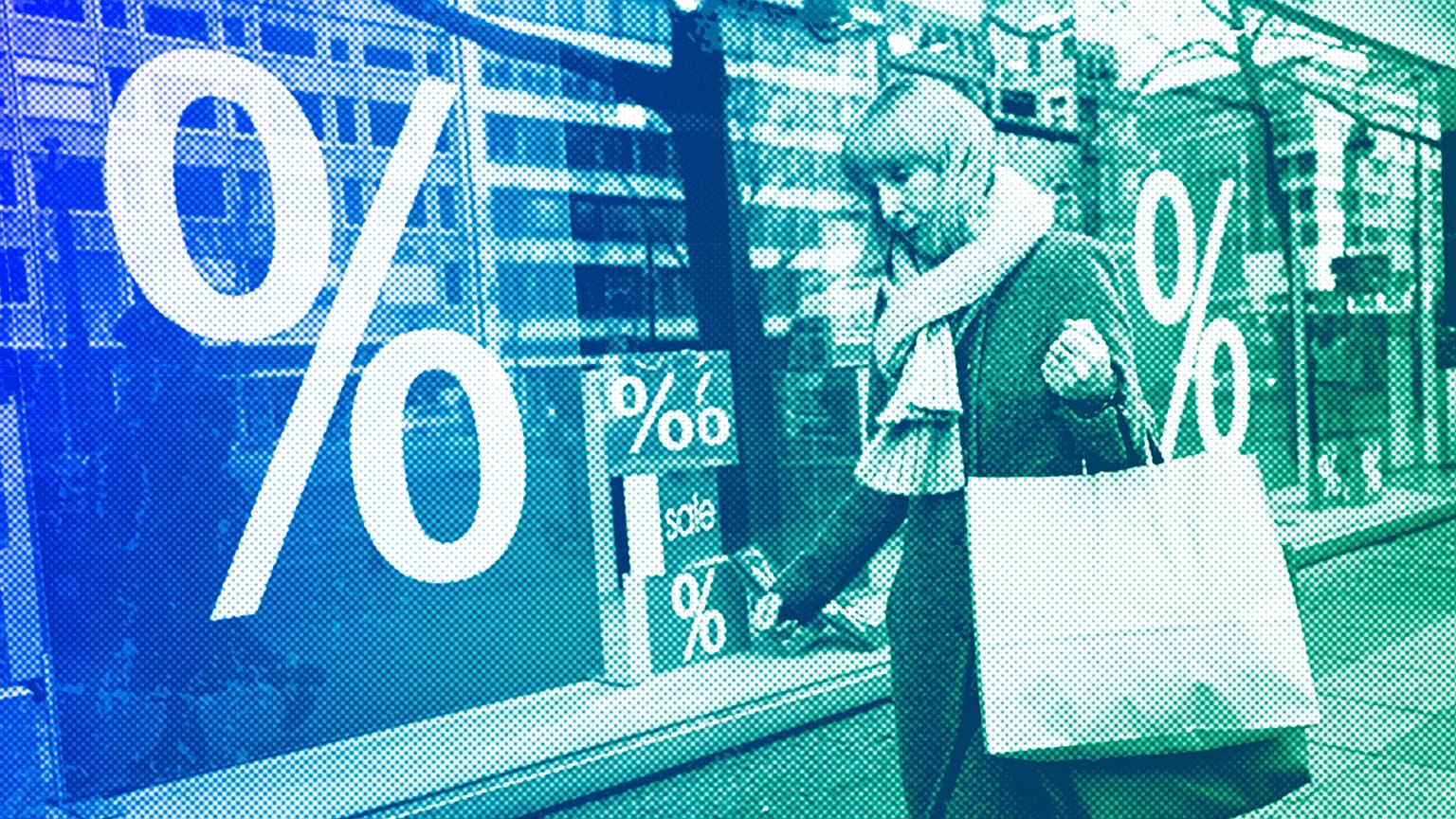 A woman walks with purchases past a store in Berlin, April 2022