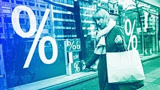 A woman walks with purchases past a store in Berlin, April 2022