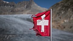 A photograph taken on August 24, 2023 above Gletsch, in the Alps shows a frayed Swiss flag next to insulating foam covering a part of the Rhone Glacier to prevent it from melt