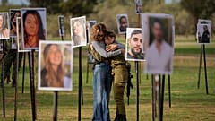 Israelis umarmen sich neben Fotos von Menschen, die von militanten Hamas-Kämpfern während ihres Amoklaufs auf dem Nova-Musikfestival im Süden Israels getötet und gefangen genommen wurden