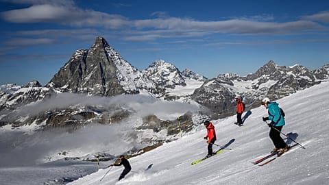 Skiers with the Matterhorn mountain as landscape near the 3,480-metre high Rifugio Guide del Cervino 