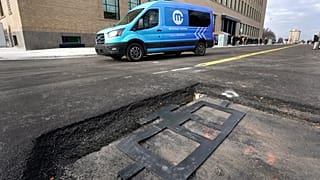 An electric van drives near a visible in-road wireless charging coil to be installed in a street in Detroit, Wednesday, November 29, 2023.