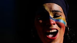 A woman, her face painted with the colours of the national flag, sings during the closing campaign on the Venezuela Referendum on dispute territory with Guyana.