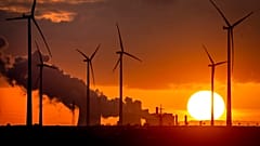 Szélturbinák hátterében egy szénerőmű füstje Németországban