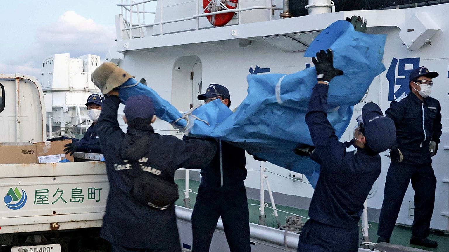 Miembros de la Guardia Costera Japonesa cargan restos de la aeronave militar estadounidense Osprey en un puerto este lunes en la prefectura de Kagoshima