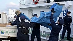 Miembros de la Guardia Costera Japonesa cargan restos de la aeronave militar estadounidense Osprey en un puerto este lunes en la prefectura de Kagoshima