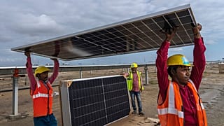 Workers carry a solar panel for installation at the under-construction Adani Green Energy Limited's Renewable Energy Park, India, 21 September 2023.