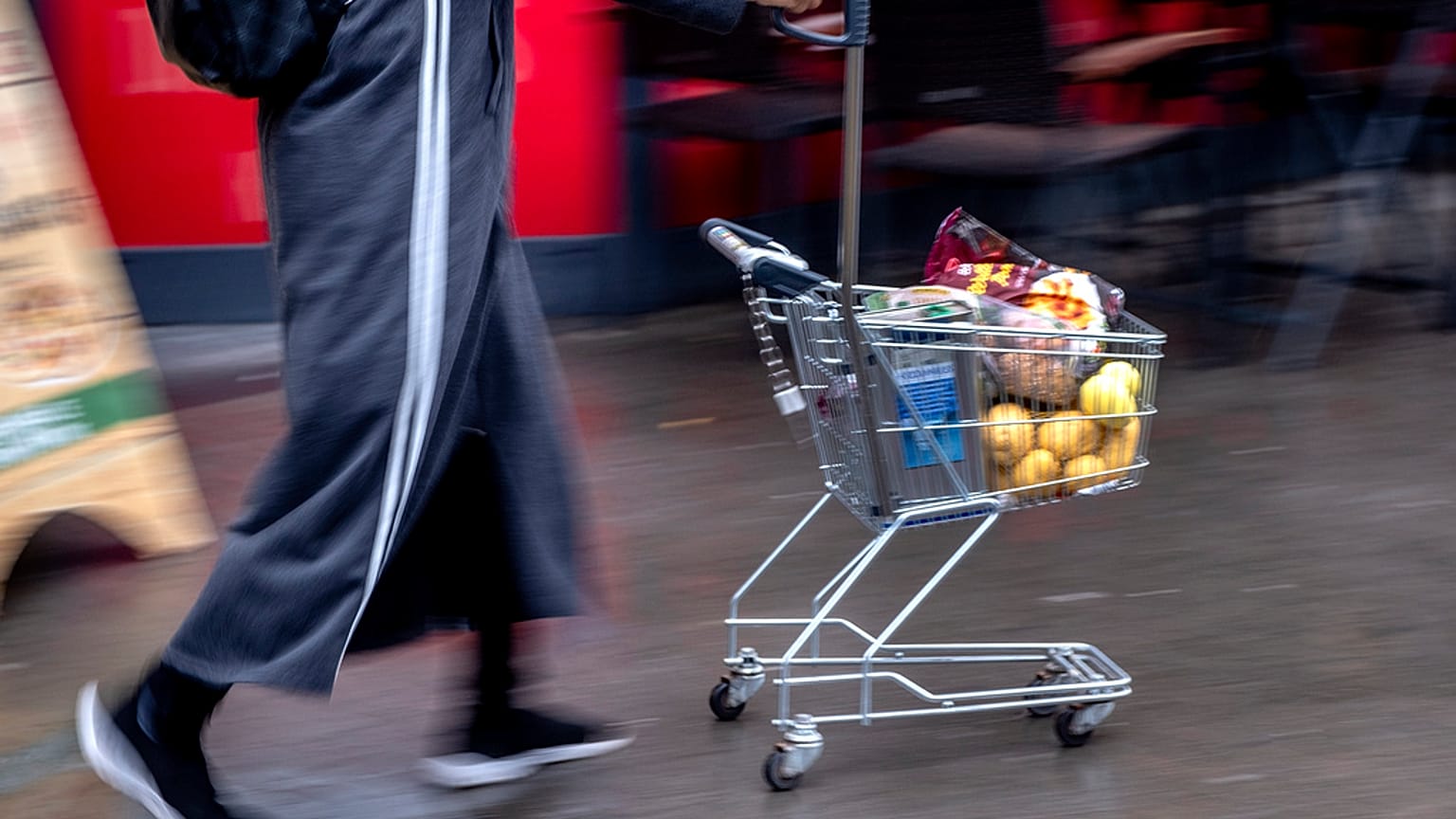 A woman pushes a small shopping cart outside a discount market in Frankfurt, Germany, Thursday, July 27, 2023. 