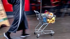 A woman pushes a small shopping cart outside a discount market in Frankfurt, Germany, Thursday, July 27, 2023. 
