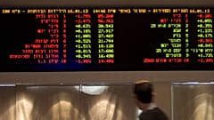 A trader walks past a board at the Tel Aviv Stock Exchange on January 16, 2011.