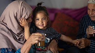 زوجان مغربيان يداعبان حفيدتهما في خيمة أصبحت تؤوي العائلة بعد أن نزحت من قرية مولاي إبراهيم التي ضربها الزلزال