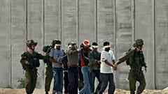 جنود إسرائيليون يرافقون أسرى فلسطينيين معصوبي الأعين بالقرب من غزة 