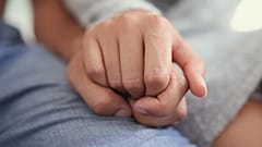 Zwei Menschen halten sich an den Händen. 