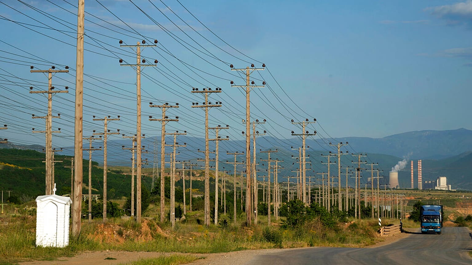 A truck passes near electricity posts as a power plant is seen in the background, near Kozani city, northern Greece, on Thursday, June 2, 2022.