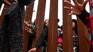 مهاجرون يصلون عبر الجدار الحدودي للحصول على الملابس التي يوزعها المتطوعون في سان دييغو