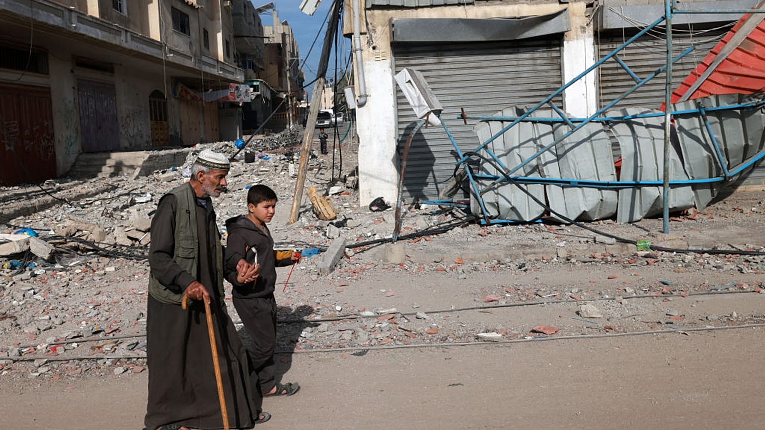 A young boy holds the hand of an old man as they walk along a street in Rafah in the southern Gaza Strip