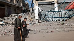 A young boy holds the hand of an old man as they walk along a street in Rafah in the southern Gaza Strip