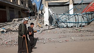 A young boy holds the hand of an old man as they walk along a street in Rafah in the southern Gaza Strip