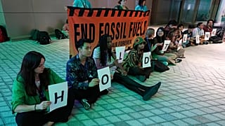Demonstrators hold signs that reads "hold the line" and "end fossil fuels" during COP28.