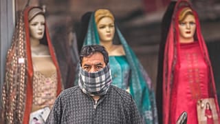Imagen de un hombre que espera al autobús, frente a una tienda de ropa, la localidad de Srinagar, Cachemira.