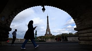 A woman checks her phone as she walks on a bridge, Thursday, Nov. 2, 2023 in Paris. (AP Photo/Aurelien Morissard)