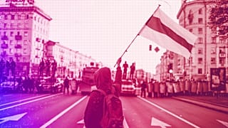 A protester waves an old Belarusian national flag walks in front of police blocking the road in Minsk, September 2020