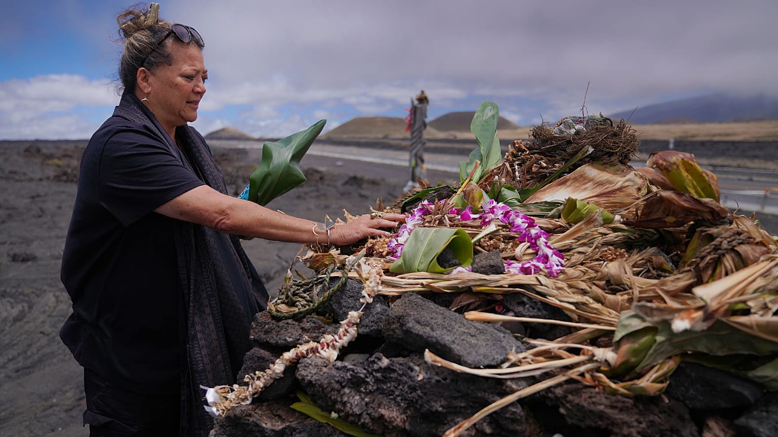 Kealoha Pisciotta, a cultural practitioner and longtime activist, lays offerings before praying at an "ahu," or ceremonial platform, part of the way up Mauna Kea 