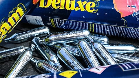 This illustration photograph taken in Lille, on May 10, 2022, shows capsules of nitrous oxide, also called "laughing gas", displayed on a table. 