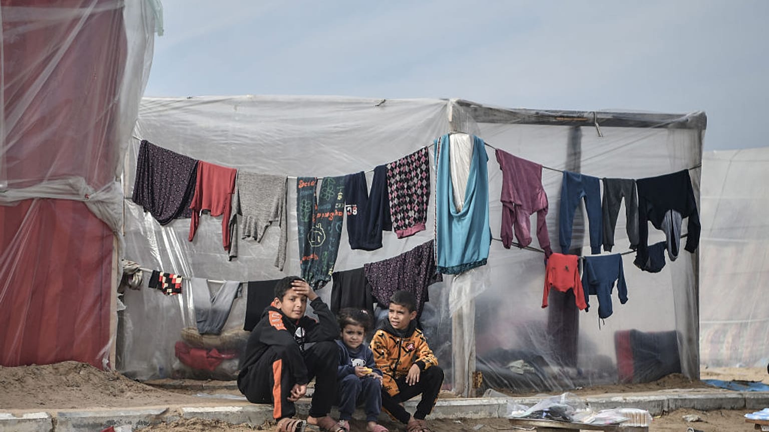 Palestinian children sit in front of tents, set up near seashore, as people try to continue their daily lives under Israeli attacks in Rafah, Gaza