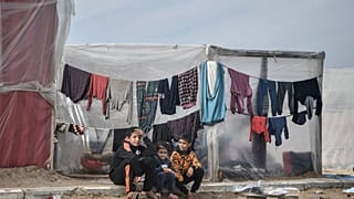 Palestinian children sit in front of tents, set up near seashore, as people try to continue their daily lives under Israeli attacks in Rafah, Gaza