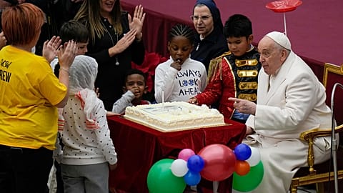 Pope Francis blows a candle on a cake as he celebrates his birthday 