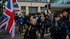 L'attivista Alexandra Wong tiene in mano una bandiera della Gran Bretagna davanti alla corte dove è previsto l'inizio del processo all'editore Jimmy Lai, a Hong Kong