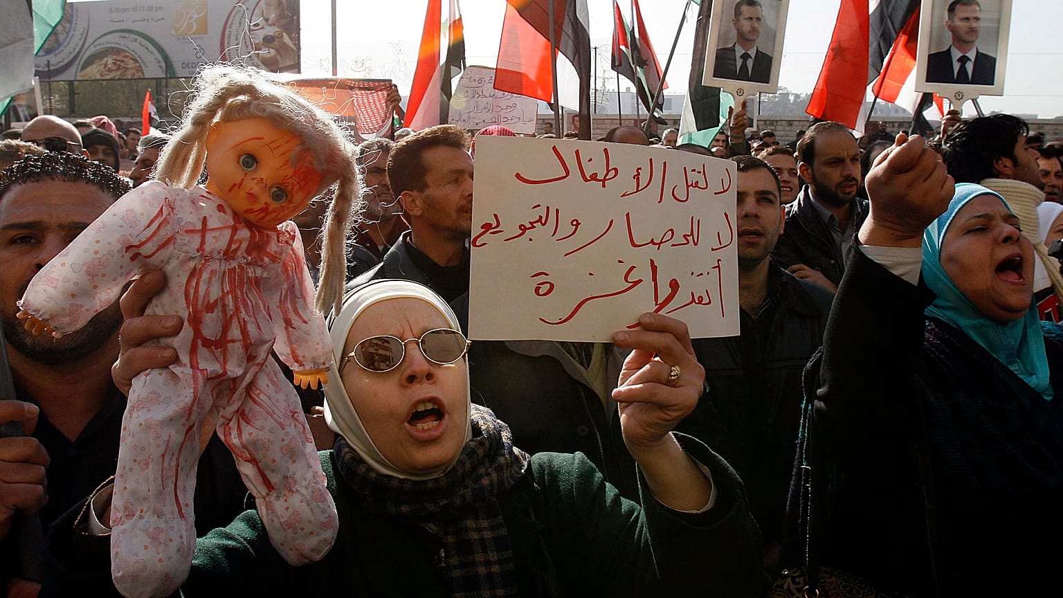 متظاهرة سورية تحمل دمية تمثل أطفال فلسطين