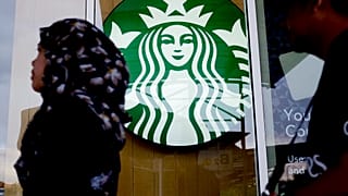 ARCHIVO - Una mujer pasa por delante de una cafetería Starbucks en Kuala Lumpur, Malasia, en julio de 2017.