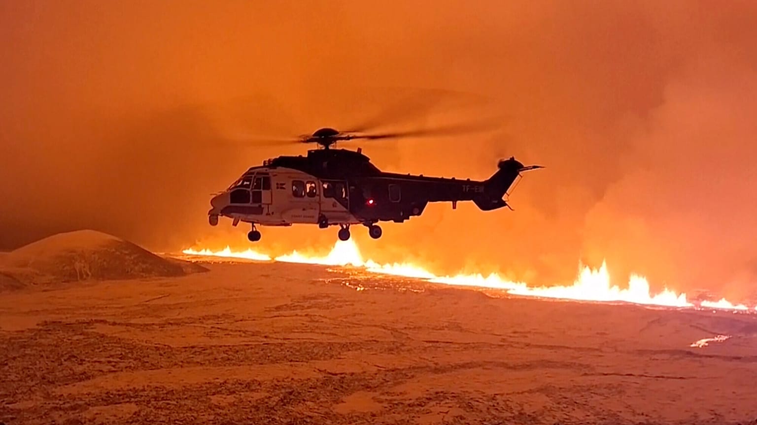 An Icelandic Coast Guard helicopter flies near magma running on a hill near Grindavik on Iceland's Reykjanes Peninsula.