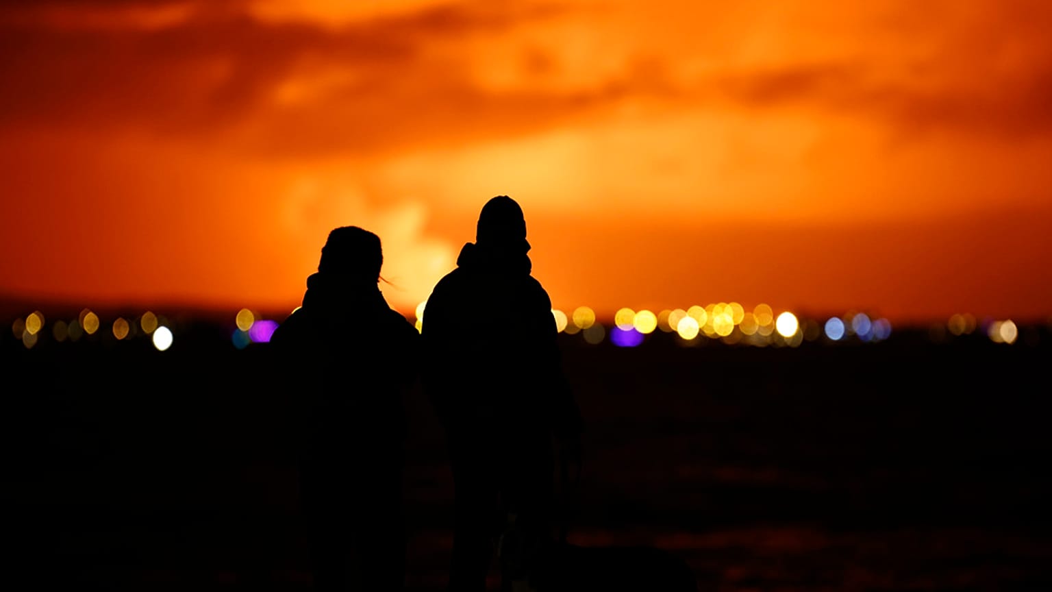 Persone osservano da RReykjavik l'eruzione di un vulcano nella penisola di Reykjanes, nel sud-ovest dell'Islanda, lunedì 18 dicembre 2023