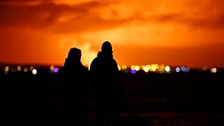 Persone osservano da RReykjavik l'eruzione di un vulcano nella penisola di Reykjanes, nel sud-ovest dell'Islanda, lunedì 18 dicembre 2023