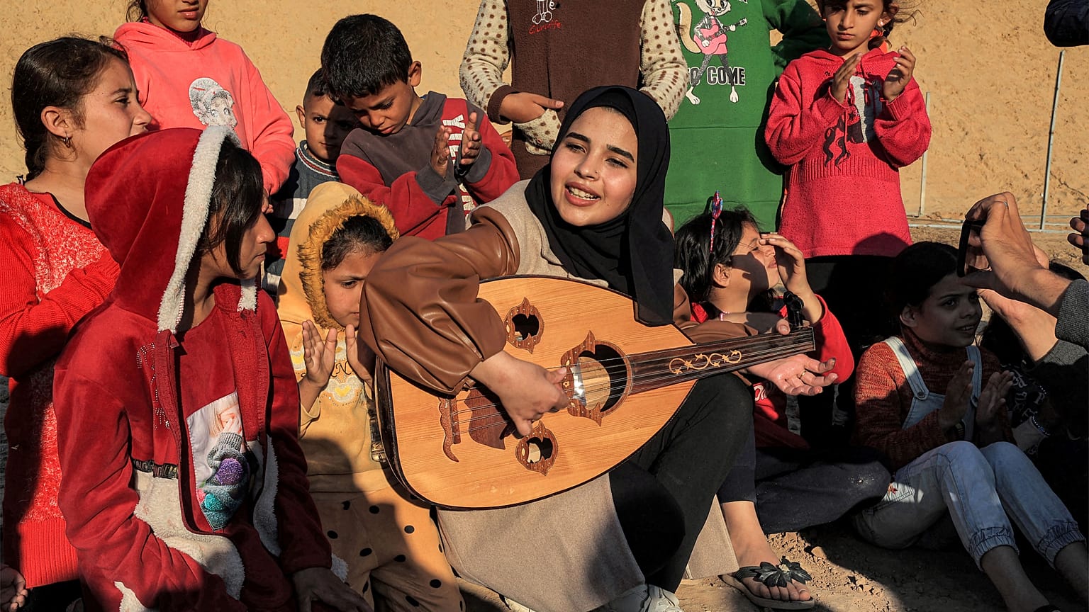  رؤيا حسونة تعزف العود وسط الأطفال في مخيم رفح