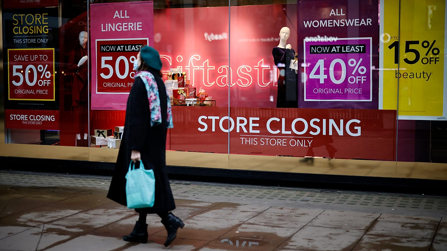 Pedestrians walk past the window display of a Debenhams shop on Oxford Street in central London on December 22, 2020.