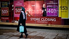 Pedestrians walk past the window display of a Debenhams shop on Oxford Street in central London on December 22, 2020.