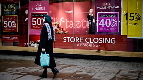 Pedestrians walk past the window display of a Debenhams shop on Oxford Street in central London on December 22, 2020.