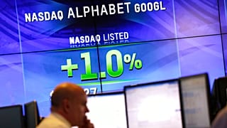 На электронных экранах отображается цена акций Alphabet.