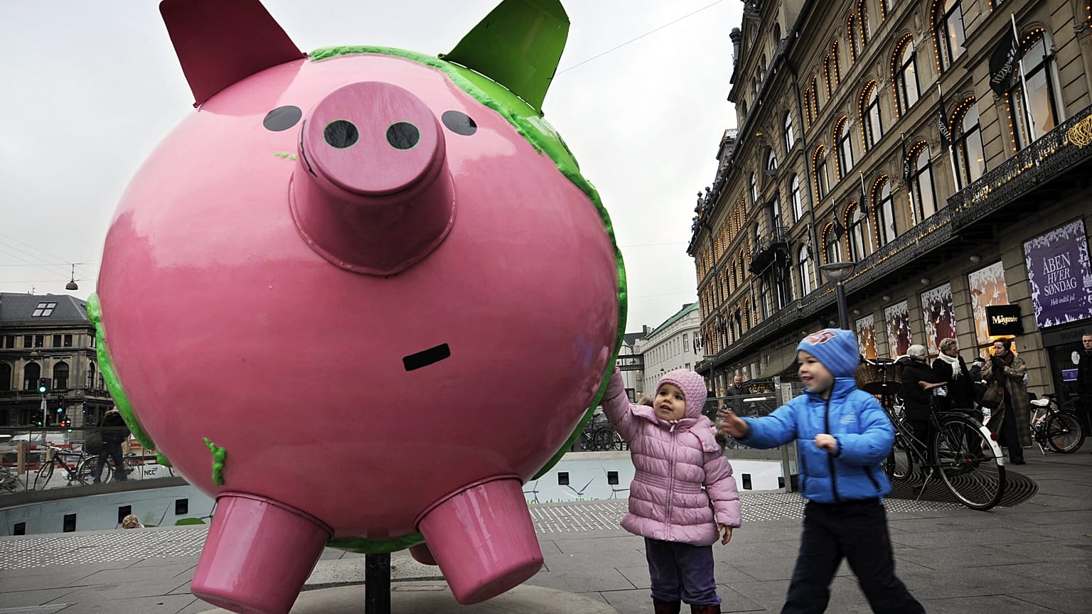 Children touch a giant model globe in the shape of a piggy bank, part of an art installation entitled "Cool Globes," about combating global warming and climate change in the K