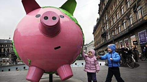 Children touch a giant model globe in the shape of a piggy bank, part of an art installation entitled "Cool Globes," about combating global warming and climate change in the K