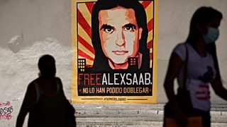مشاة يسيرون بالقرب من ملصق يطالب بحرية رجل الأعمال الكولومبي والمبعوث الخاص الفنزويلي أليكس صعب، في كاراكاس، فنزويلا