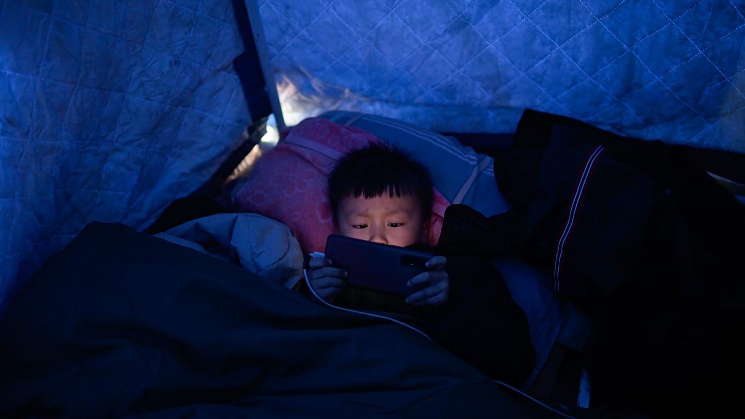 Un sobreviviente del terremoto sostiene un teléfono móvil en un refugio improvisado hecho de lona en Jishishan, en Gansu, en el noroeste de China, el 20 de diciembre de 2023.