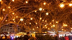 Nachts erleuchten Sterne den Weihnachtsmarkt in Straßburg.