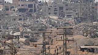 Israeli troops walk in the Gaza Strip as seen from southern Israel, Thursday, Dec. 21, 2023.